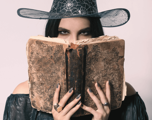 mulher segurando um livro com personagens bruxas e bruxos