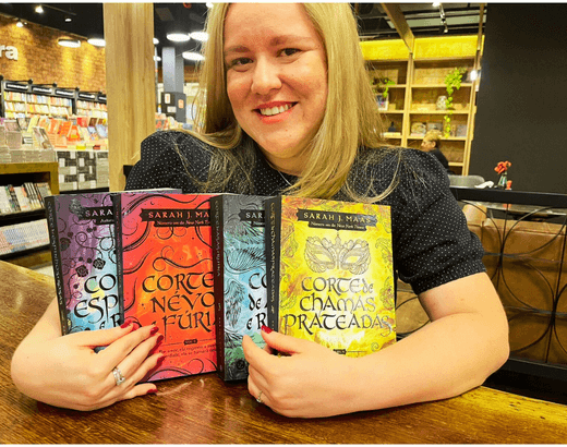 leitora segurando 4 dos 5 livros da ordem de leitura de corte de espinhos e rosas da Sarah J. Maas